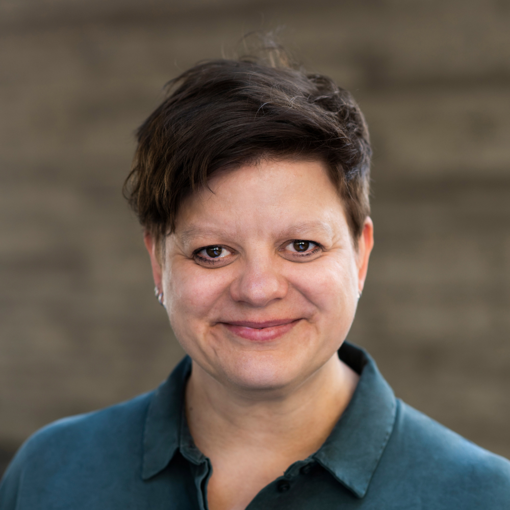 Portrait of Ulla Blume, female, fair-skinned, wearing a dark blue blouse and short brown hair